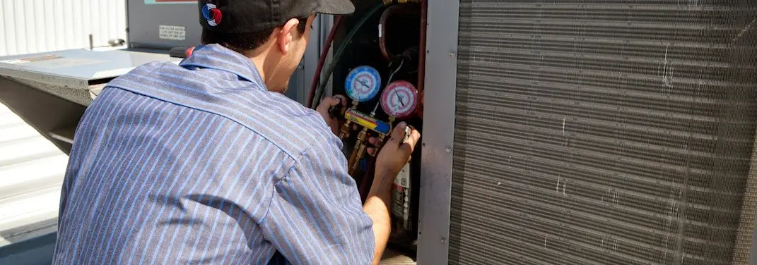 HVAC technician servicing a condenser unit in Wilkins